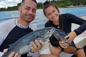man and woman on a fishing boat holding the caught fish