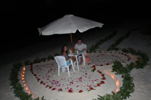 romantic dinner under an umbrella on the sandy beach in a lighted heart-shaped space