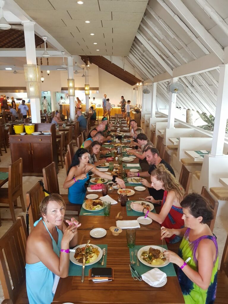 People eating food at a long dining table in a hotel space