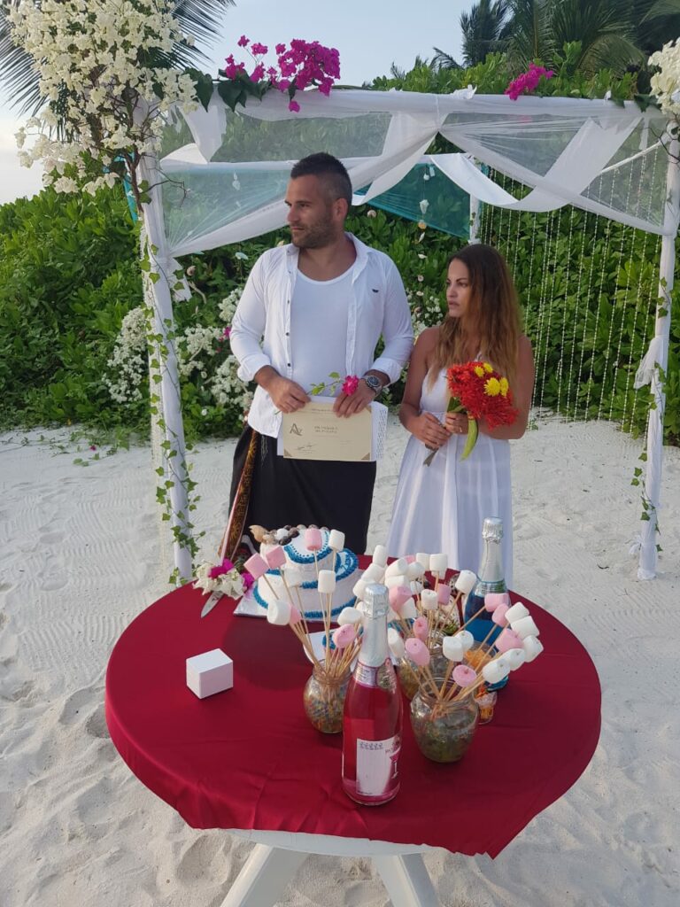 Newlyweds in front of the ceremony tent and champagne table on the sandy beach