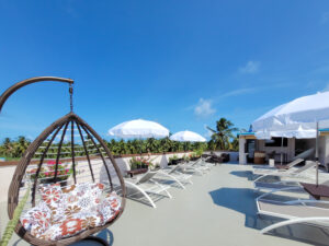 Sun loungers, parasols and a rocking chair on the roof terrace overlooking the palm trees.