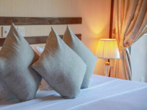 3 arranged pillows on the bed with a lighted lamp in the background
